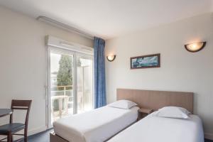 um quarto de hotel com duas camas e uma janela em Appart'City Classic Antibes em Antibes