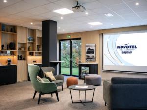 a living room with a projection screen and furniture at Novotel Bayeux in Bayeux