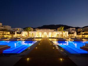 uma piscina à noite com luzes azuis em Anemos Luxury Grand Resort em Georgioupolis