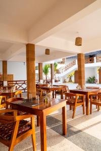an empty restaurant with wooden tables and chairs at S&S HOTEL in Jambiani