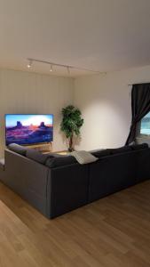 a large black couch in a living room with a flat screen tv at Kirkenes down town apartments in Kirkenes