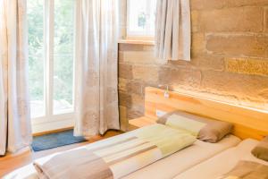 a bed in a room with a brick wall at Hellbachhof in Equarhofen