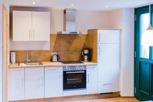 a kitchen with white cabinets and a sink and a stove at Hellbachhof in Equarhofen