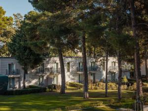 a white building with trees in front of it at Grecotel Larissa Imperial in Larisa