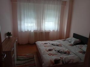 a bedroom with a bed and a window with curtains at Apartament MaTei in Timişoara