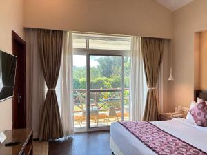a bedroom with a bed and a large window with a balcony at Resort De Coracao - Corbett , Uttarakhand in Rāmnagar