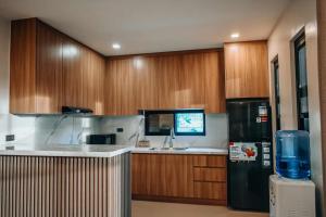 a kitchen with wooden cabinets and a black refrigerator at Casa De Una Tagaytay in Galicias