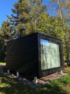 a black building with a window in the grass at HALLA-mökki in Tyrnävä