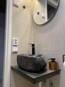 a bathroom with a stone sink and a mirror at HALLA-mökki in Tyrnävä