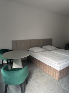 a bedroom with a bed and a table and a green chair at Hotel Johannisberg Bad Homburg in Bad Homburg vor der Höhe