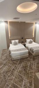 two beds in a hotel room with a ceiling at عز الاصالة للشقق المخدومة تصنيف اقتصادي in Taif +5 photos