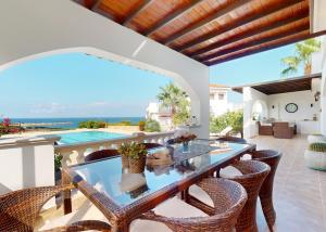 an outdoor dining room with a glass table and chairs at Villa Olive View in Kyrenia