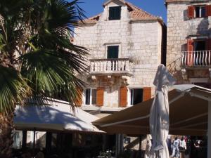 an umbrella and a building with a balcony at Apartment House Vitaic in Supetar