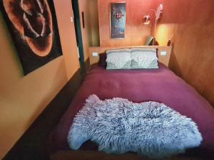 a bedroom with a purple bed with a furry rug on it at Nordic Noir Cabin in Queenstown