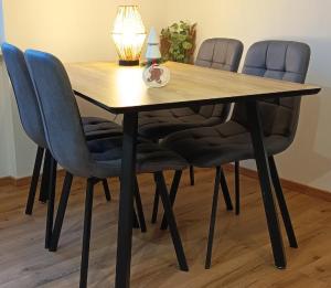 a wooden table with four chairs and a lamp at Apartmán U nás in Malá Morávka