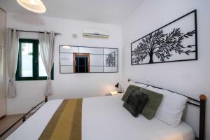 a bedroom with a white bed with a tree picture on the wall at Outstanding Apartment in an Unique Aegean Inspired Settlement in Agia Triada