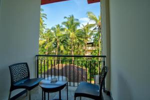 a balcony with chairs and a table and palm trees at Dimaru Boutique Hotel in Calangute