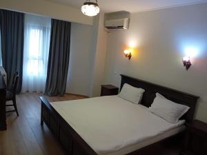 a bedroom with a large bed with white sheets at Hotel Majestic in Iaşi