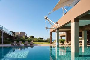 a swimming pool with lounge chairs next to a building at Atlantica Mikri Poli Crete in Makry Gialos