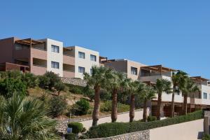 a row of apartment buildings with palm trees at Atlantica Mikri Poli Crete in Makry Gialos