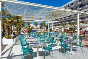 an outdoor dining area with blue chairs and tables at Tigotan Lovers & Friends Playa de las Americas - Adults Only (+18) in Playa de las Americas