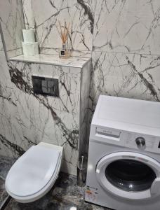 a bathroom with a toilet and a washing machine at AFI Discret Jacuzzi in Bucharest