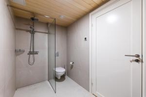 a bathroom with a toilet and a glass shower at Komandandi Smart Stay City Center Apartments in Kuressaare