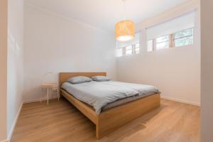a white bedroom with a bed and a window at Komandandi Smart Stay City Center Apartments in Kuressaare