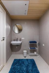 a bathroom with a sink and a mirror and a blue rug at Komandandi Smart Stay City Center Apartments in Kuressaare