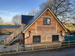 a log cabin with a wooden fence in front of it at Upper Gelli Luxury Holiday Lodge, Converted Dairy & Cosy Shepherds Huts in Welshpool