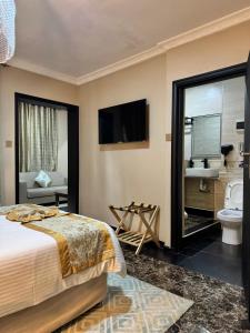 a bedroom with a bed and a tv and a bathroom at Annavilla7 Lilongwe hotel in Lilongwe
