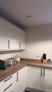 a kitchen with white cabinets and wooden counter tops at Superb Spacious Farm House in Henley on Thames