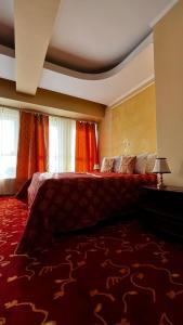 a bedroom with a large bed with a red rug at Hotel Mara in Baia Mare
