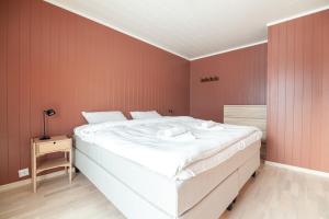 a large white bed in a room with red walls at Seaside Apartment in Lofoten - Sea Views in Ballstad