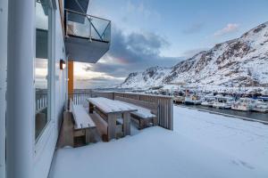 a balcony with snow covered benches and a marina at Seaside Apartment in Lofoten - Sea Views in Ballstad
