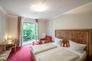 a hotel room with a bed and a desk and a window at Langwieder See in Munich