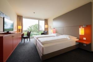 a hotel room with a large bed and a television at ATLANTIC Hotel Galopprennbahn in Bremen +40 photos