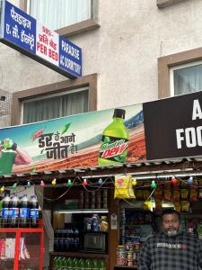 a man standing in front of a store with a large bottle of soda at PARADISE AC DORMITORY in Bareilly