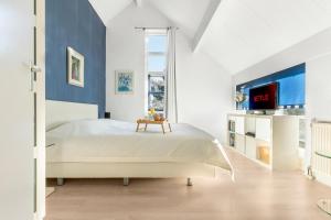 a white bedroom with a bed and a tv at Villa Beach & Golf in Julianadorp