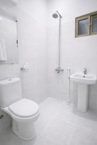 a white bathroom with a toilet and a sink at City View Residence in Islamabad