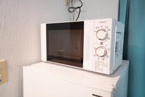 a microwave oven sitting on top of a refrigerator at Mary's Room Sumiyoshi in Sumiyoshi +27 photos