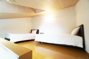 two beds in a room with white walls and wooden floors at Mary's Room Sumiyoshi in Sumiyoshi
