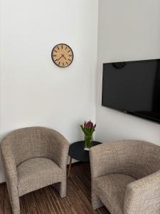 two chairs and a table with a clock on a wall at Ubytování pod Borovou in Malenovice
