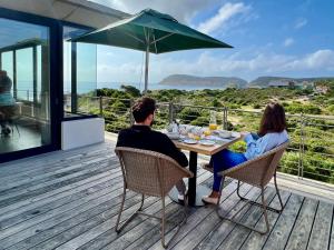 a man and woman sitting at a table on a deck at Christiana Lodge in Plettenberg Bay +18 photos