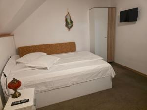 a bedroom with a white bed with white sheets at Cabana Maly in Petroşani