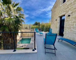 a balcony with blue chairs and a swimming pool at Cocon en petite Camargue in Aimargues