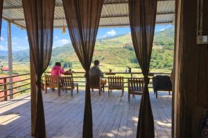 two people sitting at a table on a porch with a view at PaoDzung Homestay Sapa in Sapa