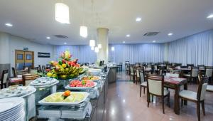 un comedor con mesas y sillas con comida. en Comfort Hotel Manaus, en Manaus