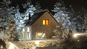 a house with a lit up window in the snow at Boroviti Mountain House in Blidinje