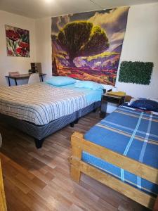 two beds in a room with a painting on the wall at El valle in Copiapó